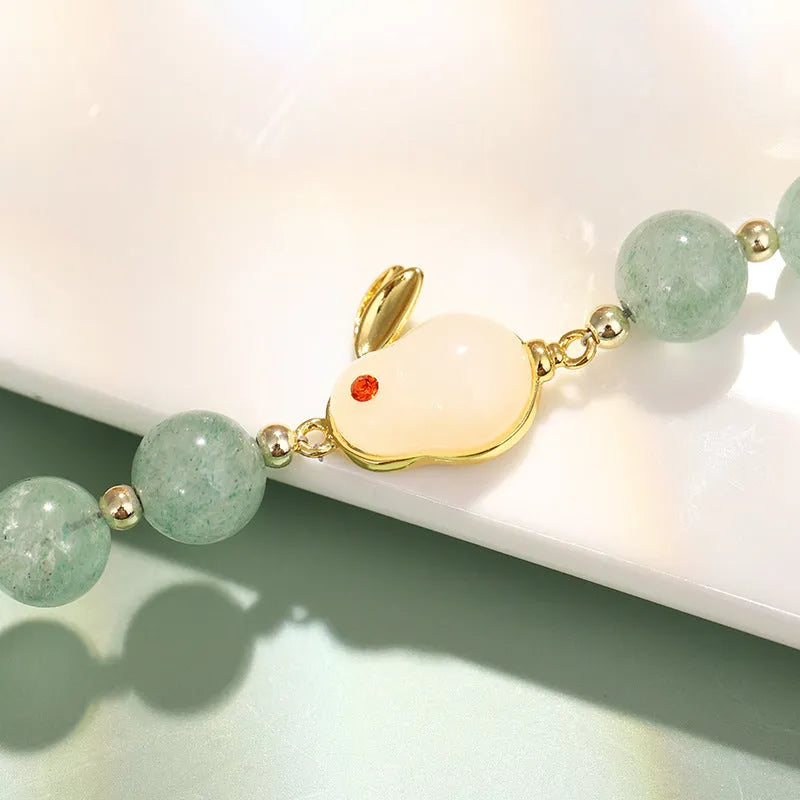 Rabbit charm bracelet with green aventurine or strawberry quartz beads on a gold-coloured adjustable chain.