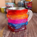 A painted synthetic resin coffee cup ornament with a bookmark design on its side.