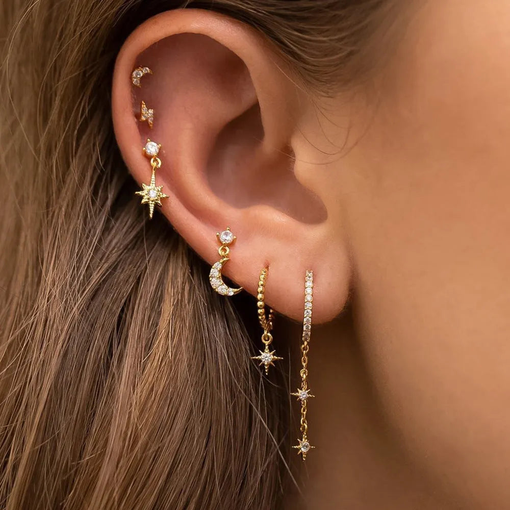 Set of six gold-coloured women's earrings with chain tassel designs and zircon studs on a white background.