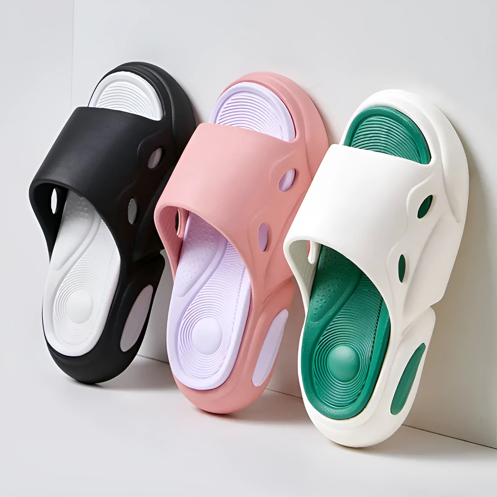 Two-colour EVA slippers for couples in pink and purple, shown on a wooden floor.