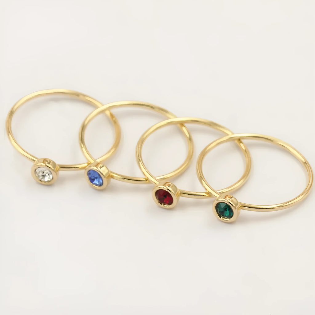 Women's 14K gilded gold-filled zircon copper knuckle ring in green, blue, dark red, or white on a finger.