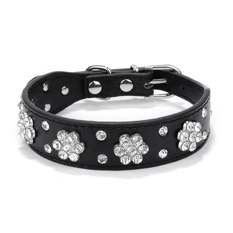 Close-up of a black PU leather dog collar with sparkling rhinestone flowers and a metal D-ring.