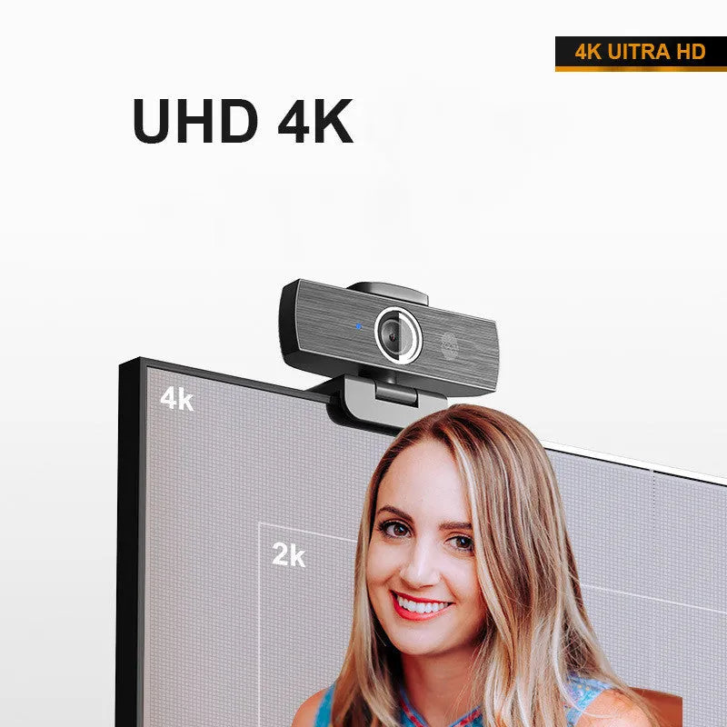 Black USB webcam with magnetic privacy cover on desk next to computer monitor