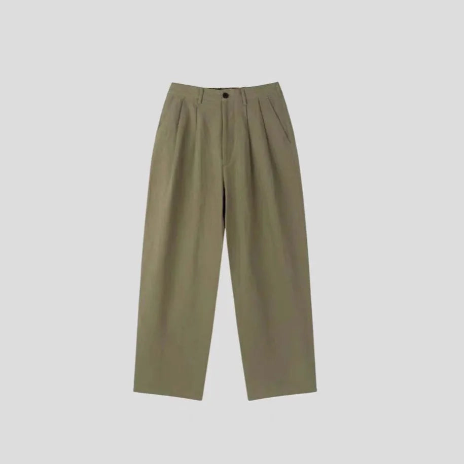 Man wearing apricot coloured loose wide-leg cotton linen trousers with a pencil leg opening.