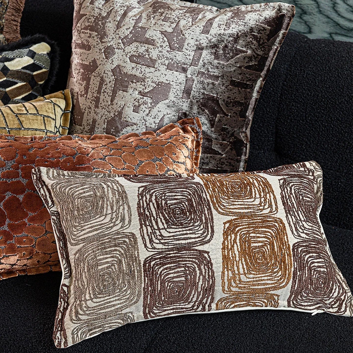 Cream and coffee-coloured abstract coil pattern on a square polyester pillow cover.