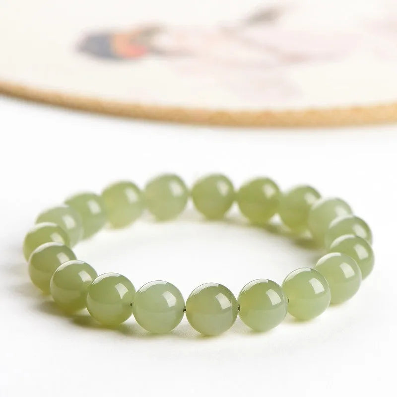Hetian jade ball bracelet with polished beads in clear water colour on a string.