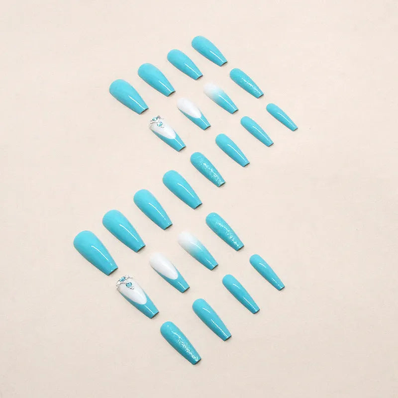 Long ballet shaped artificial nail patches with blue diamond glitter on a solid colour background, shown with a bottle of nail glue.