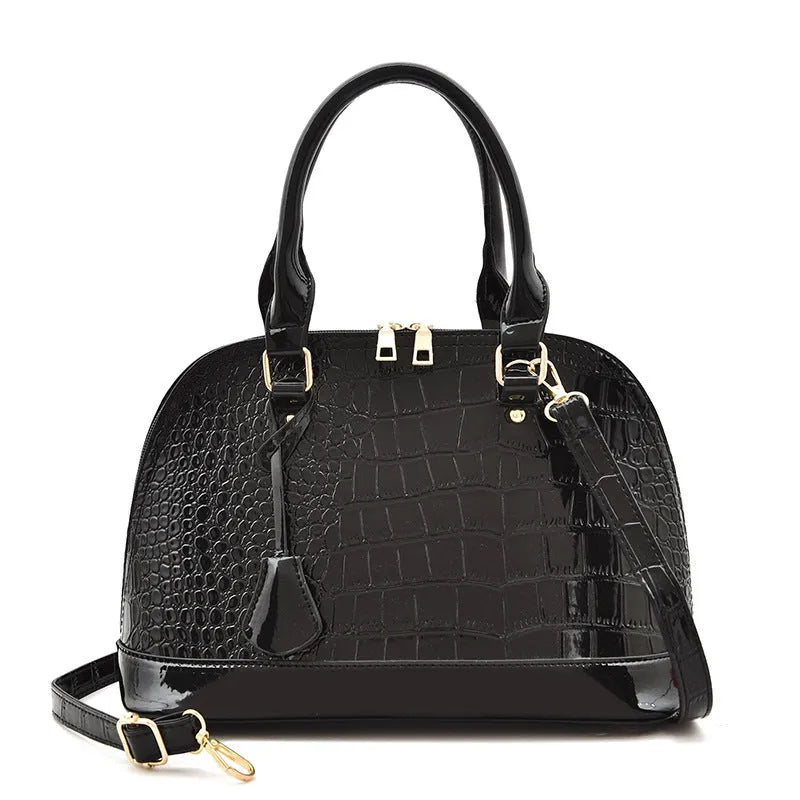 Large shiny PU crossbody shoulder bag in structured shell shape showing black, red, and brown colour options