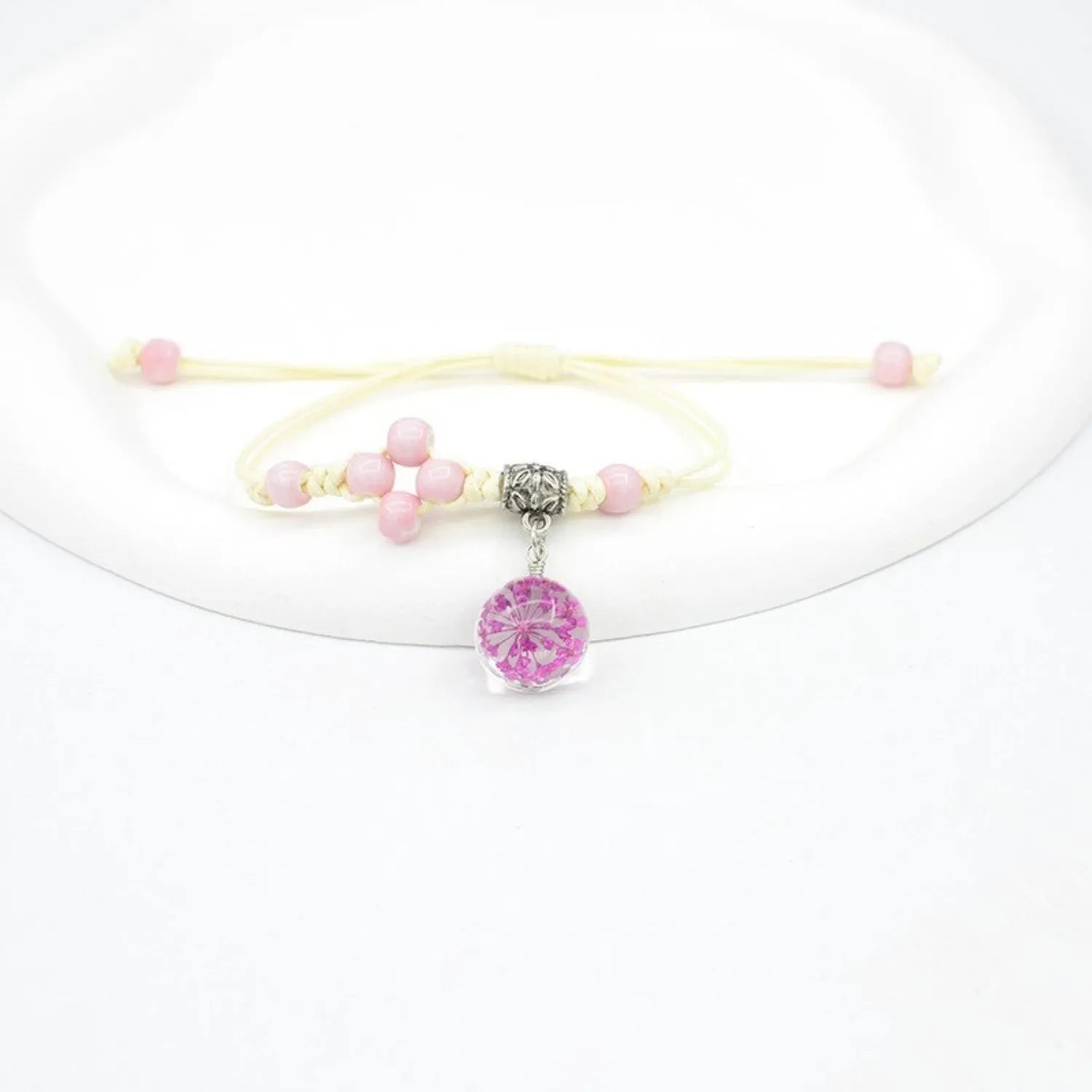 Close-up of a hand-woven glass bracelet with large 1.4 cm beads containing real dried flowers in multiple colour options.
