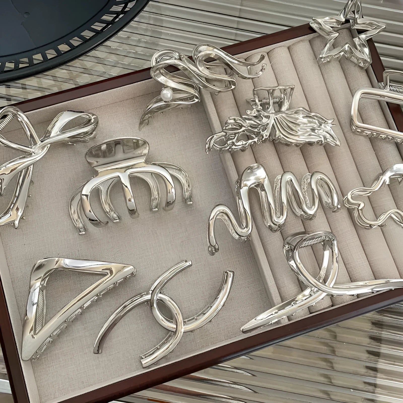 Silver metal hair claw clip assortment showing bows, waves, pearl designs, and geometric shapes from 4cm to 13.5cm