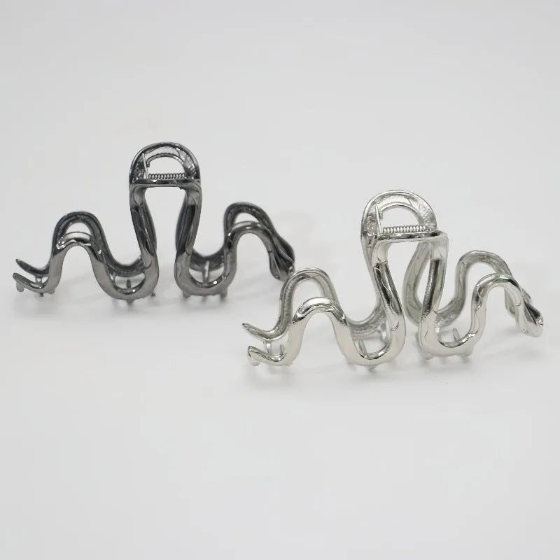 Silver metal Slytherin serpentine hair clip barrette measuring 10.5cm on a dark background