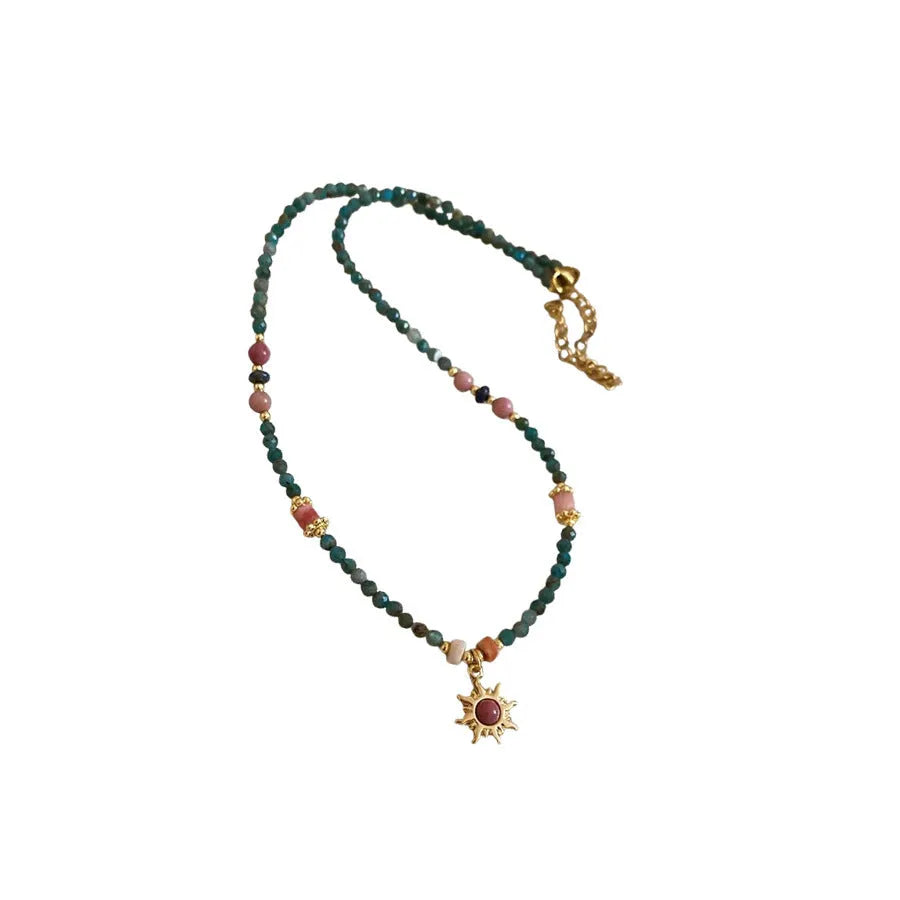 French royal style sun necklace with freshwater pearls and a blue stone geometry pendant on a gold chain.