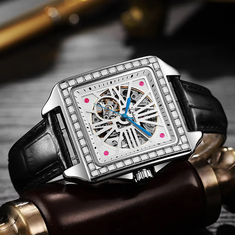 Square silver men's automatic watch with diamond-studded bezel on a black leather strap.