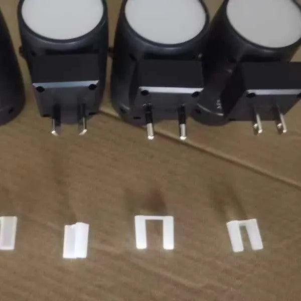 Small white adjustable plug-in night lamp with rotatable head shown in a bedside socket