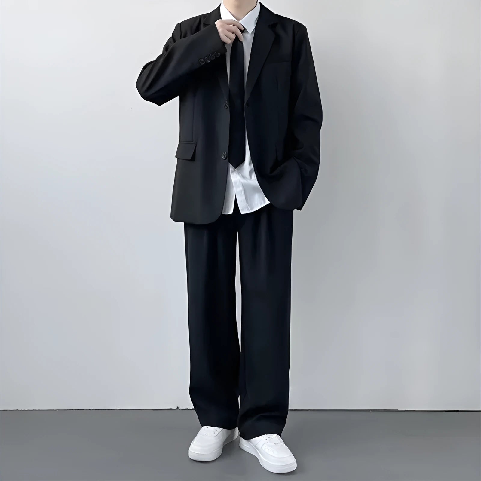 Plus size man modelling a loose fit black suit jacket and trousers with a white shirt and tie.