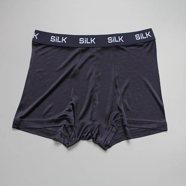 Man wearing loose fit navy blue silk shorts with a mid waist design.
