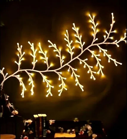 Flexible LED willow vine garland with warm white lights on birch-textured branches for wall and party decor.