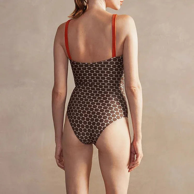 Women's printed dot pattern one-piece swimsuit with matching wrap skirt on a hanger.