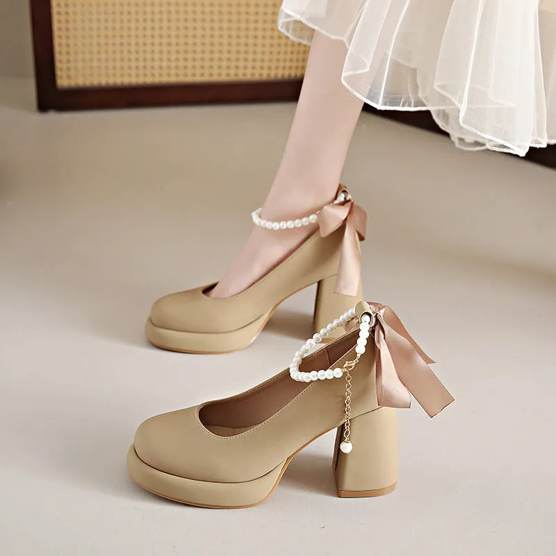 Women's beige Mary Jane shoes with chunky low heel, pearl decoration, and ankle strap buckle on a round toe.