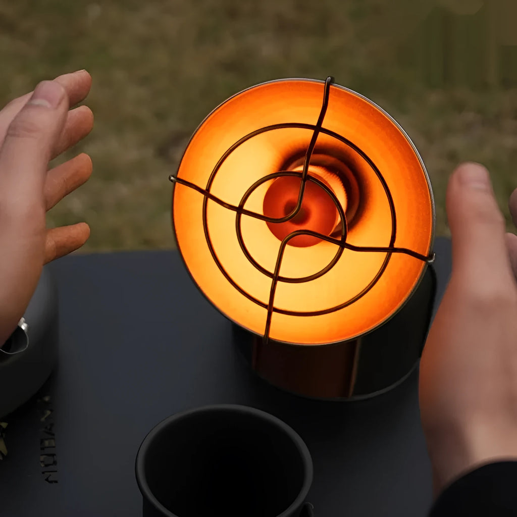 Black and orange portable camping heater stove with automatic ignition on a table.