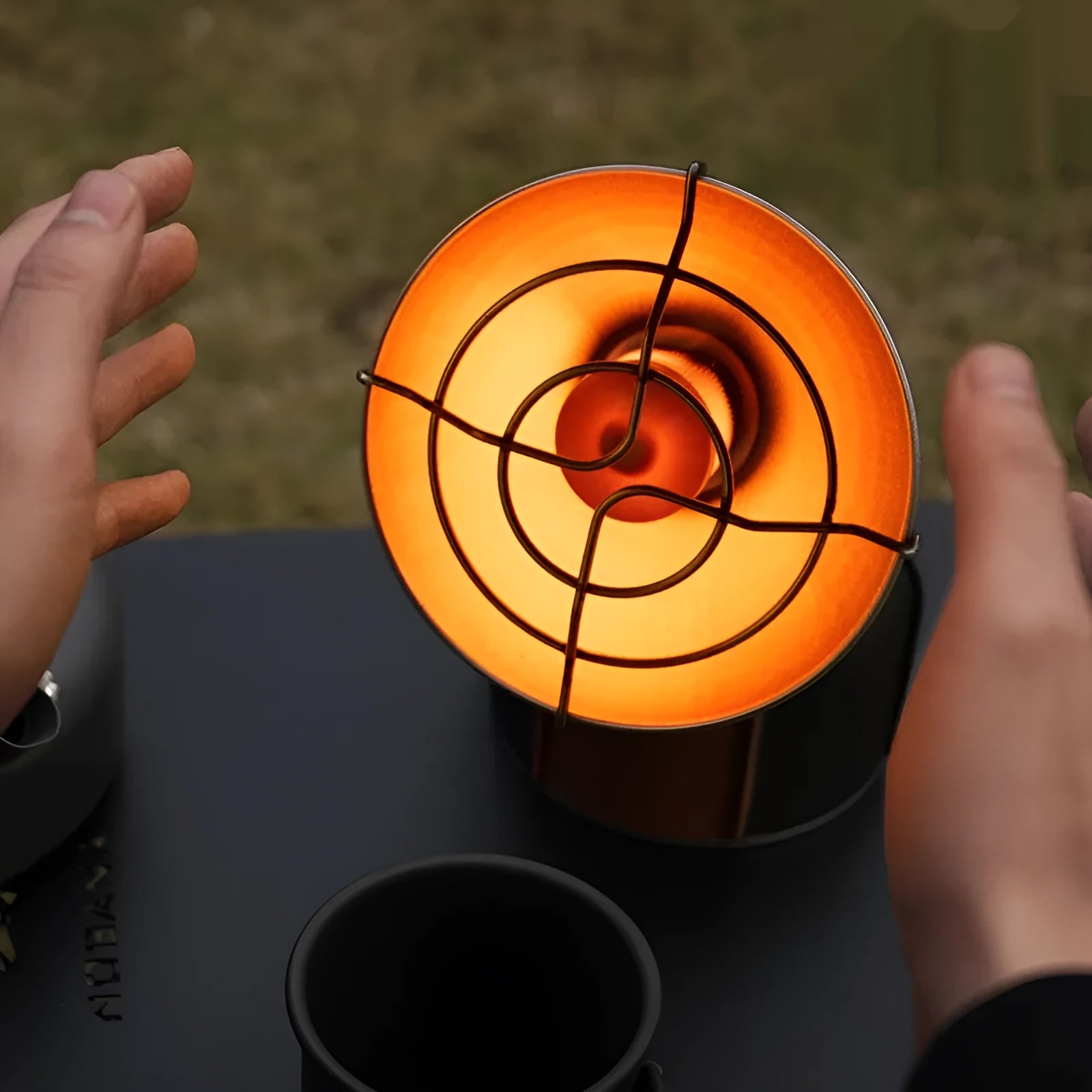 Black and orange portable camping heater stove with automatic ignition on a table.