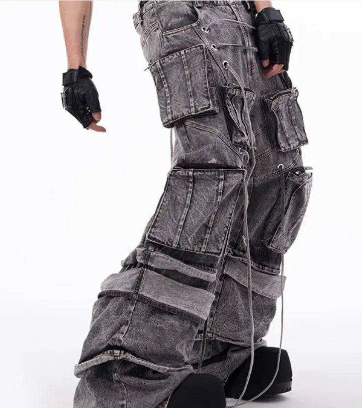 Grey distressed denim overalls with rope stitching detail on a hanger.