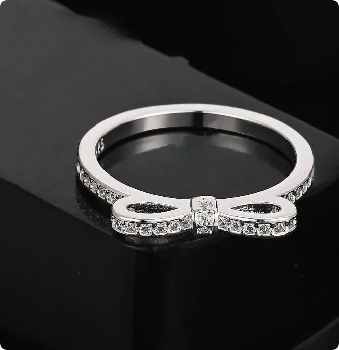 Silver bow-shaped ring with rhinestone and zircon crystal detailing on electroplated metal