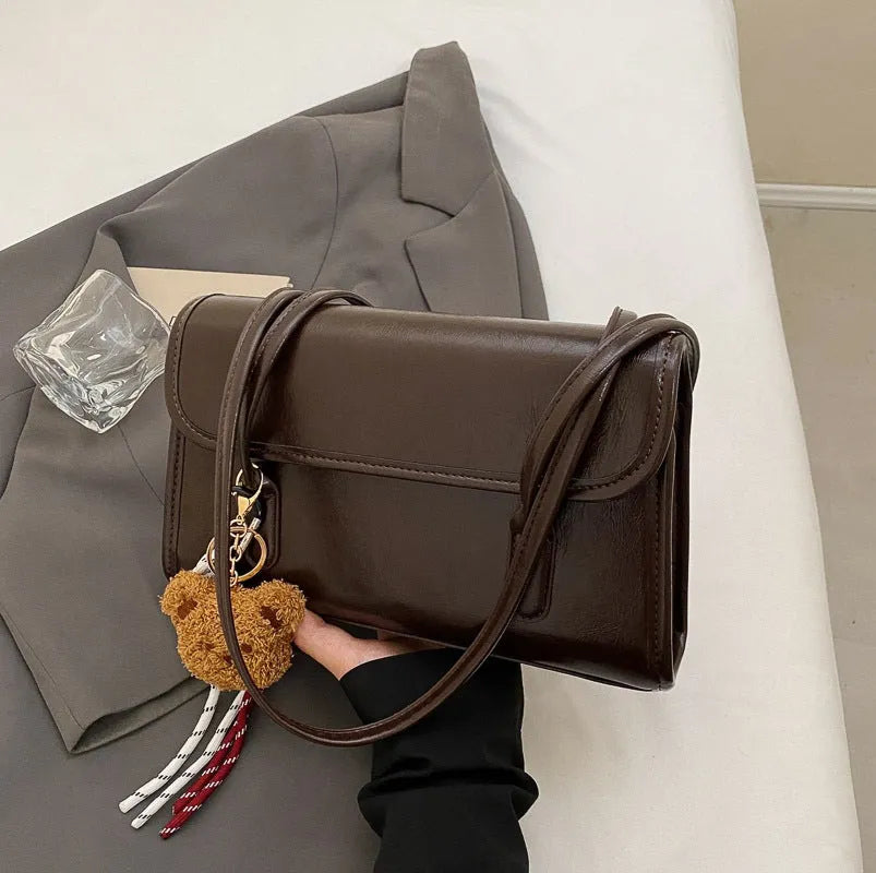 Women's brown PU leather shoulder bag with square shape, double straps, and decorative pendant attachment
