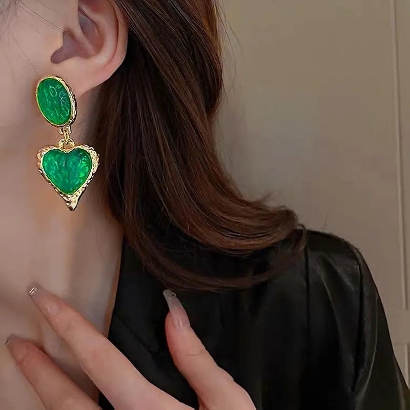 A pair of pleated oval love heart stud earrings in alloy, showing the silver needle post.