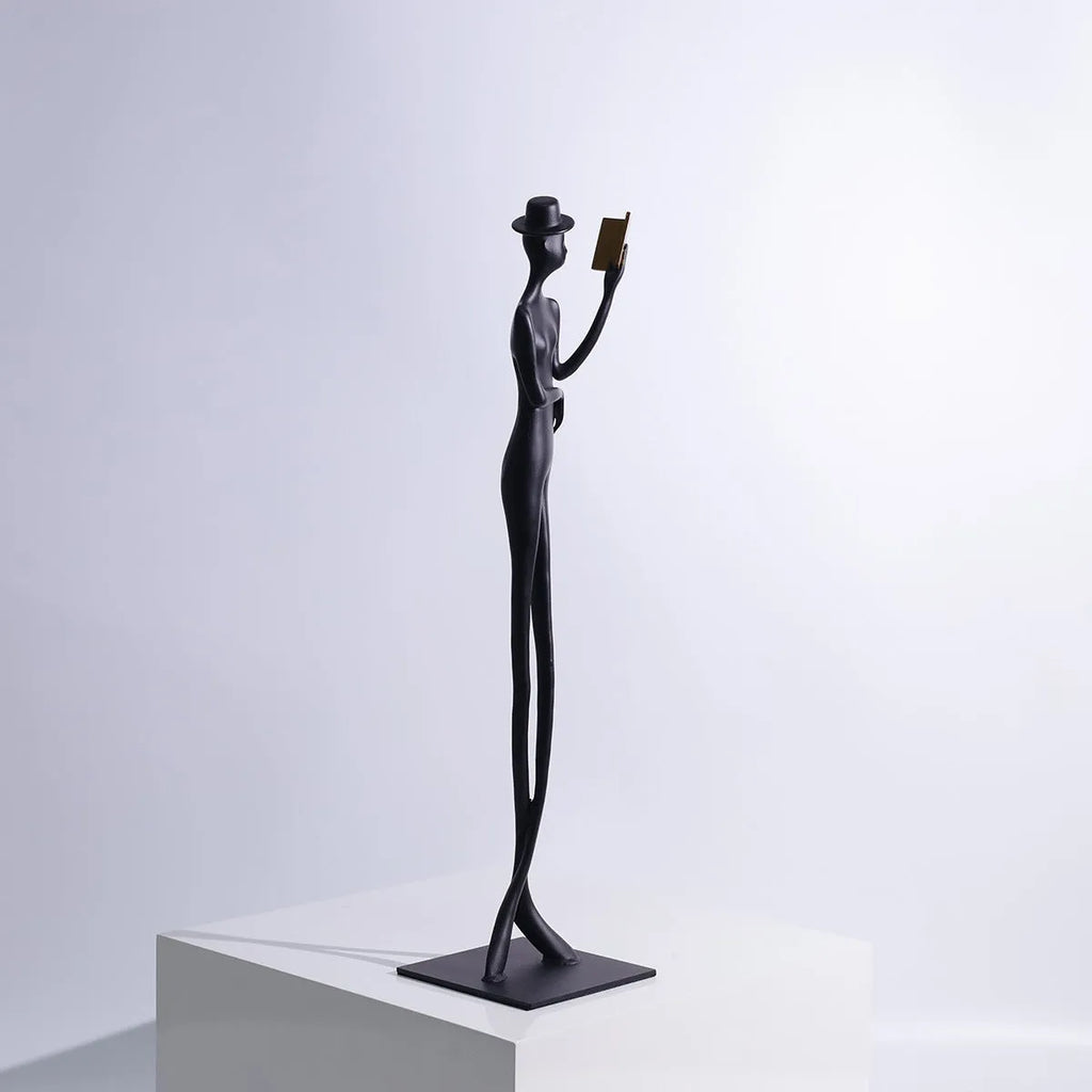 Black metal desktop sculpture of a woman reading, 51cm tall.
