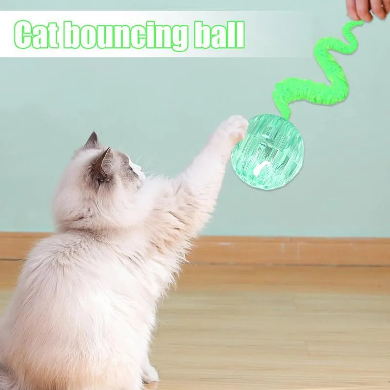 Green interactive cat toy featuring a bouncy ball with a long plush tail on a wooden floor.