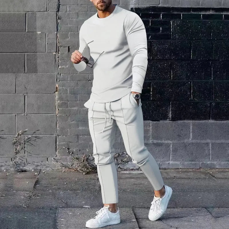 Men's light grey polyester two-piece suit with long sleeve round neck T-shirt and matching trousers laid flat.