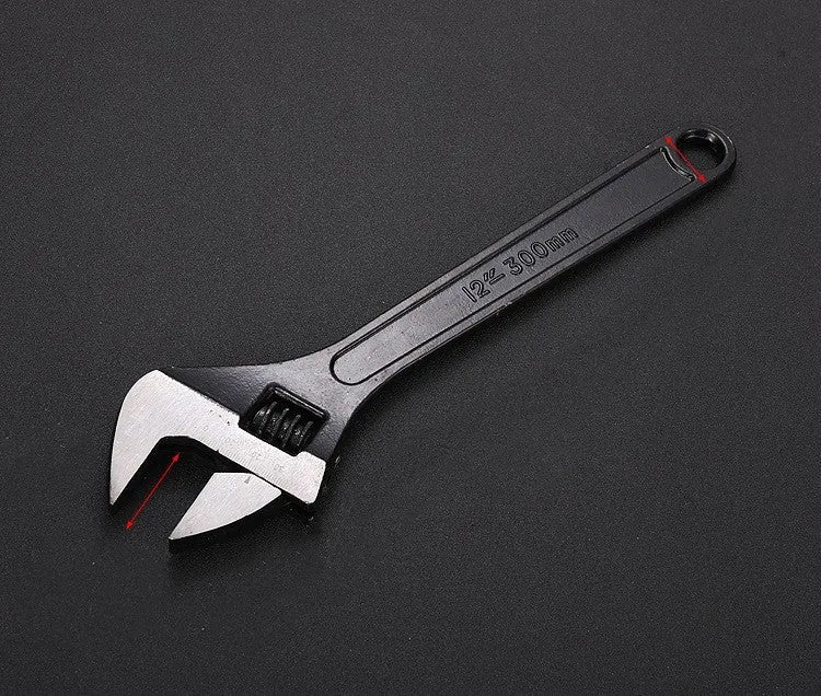 Black stainless steel adjustable open-end wrench on a workbench, showing size markings and ergonomic handle.