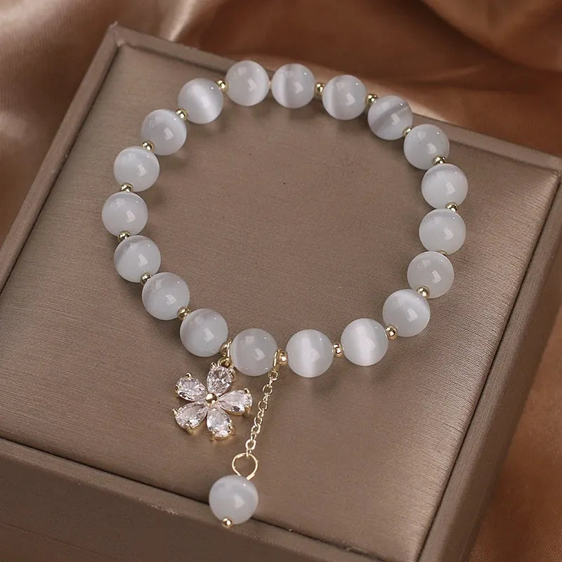 Women's white cat's eye stone bracelet with flower tassel and safety buckle pendant.