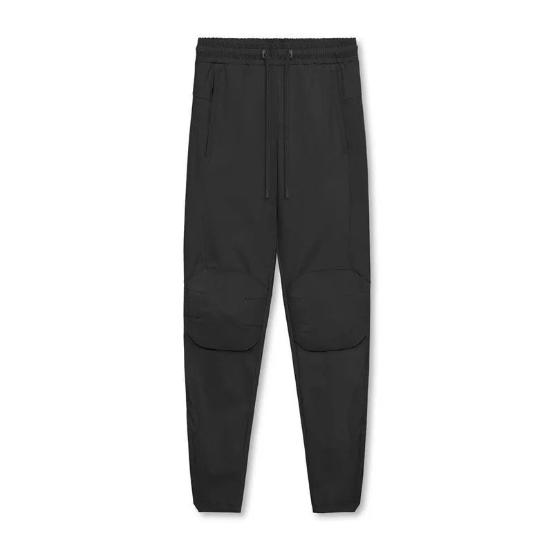Men's loose grey fitness trousers with ankle ties on a gym floor.