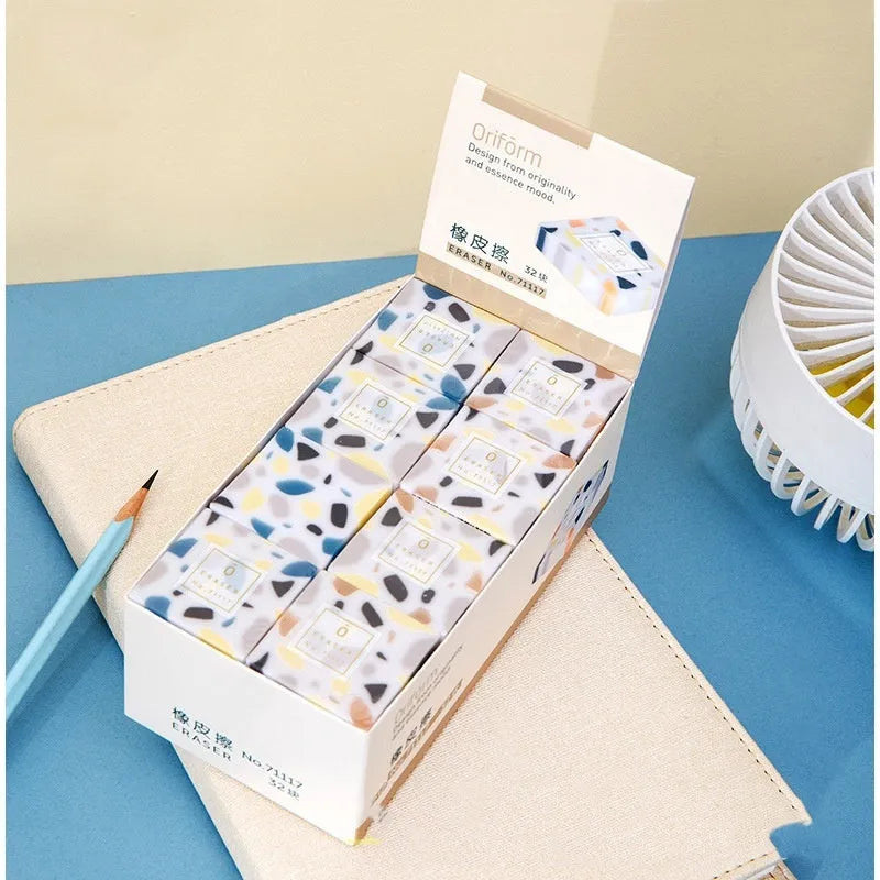 White brick-shaped rubber eraser on a surface, a stationery tool for pencil mark removal.