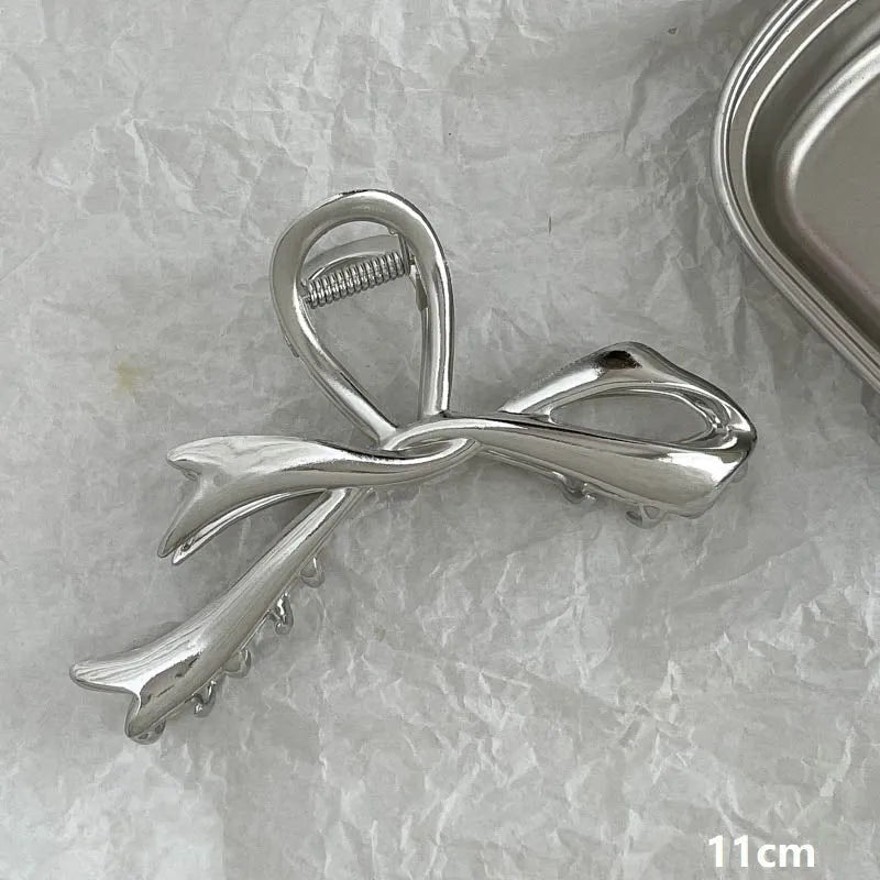 Silver metal hair claw clip assortment showing bows, waves, pearl designs, and geometric shapes from 4cm to 13.5cm
