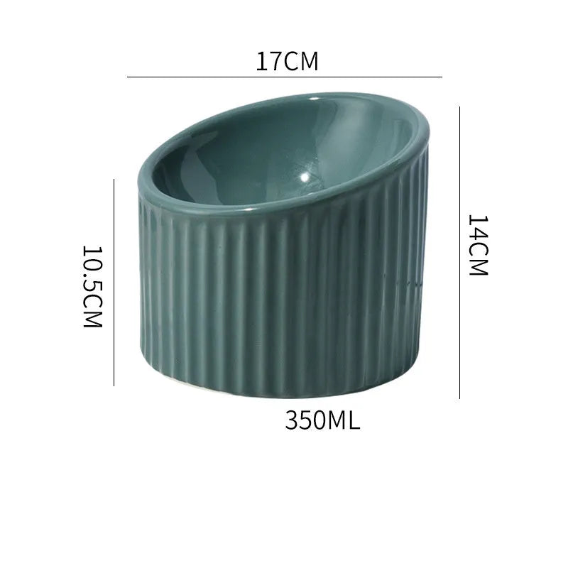 Dark green ceramic elevated cat bowl with tilted, round whisker-friendly design on a wooden floor.