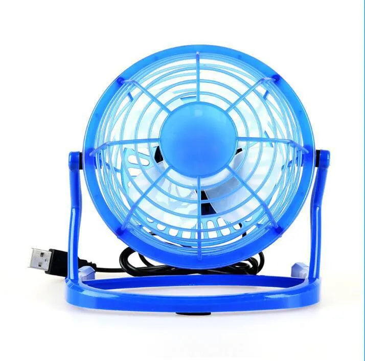 Black mini USB desk fan with adjustable head on a wooden desk next to a laptop.