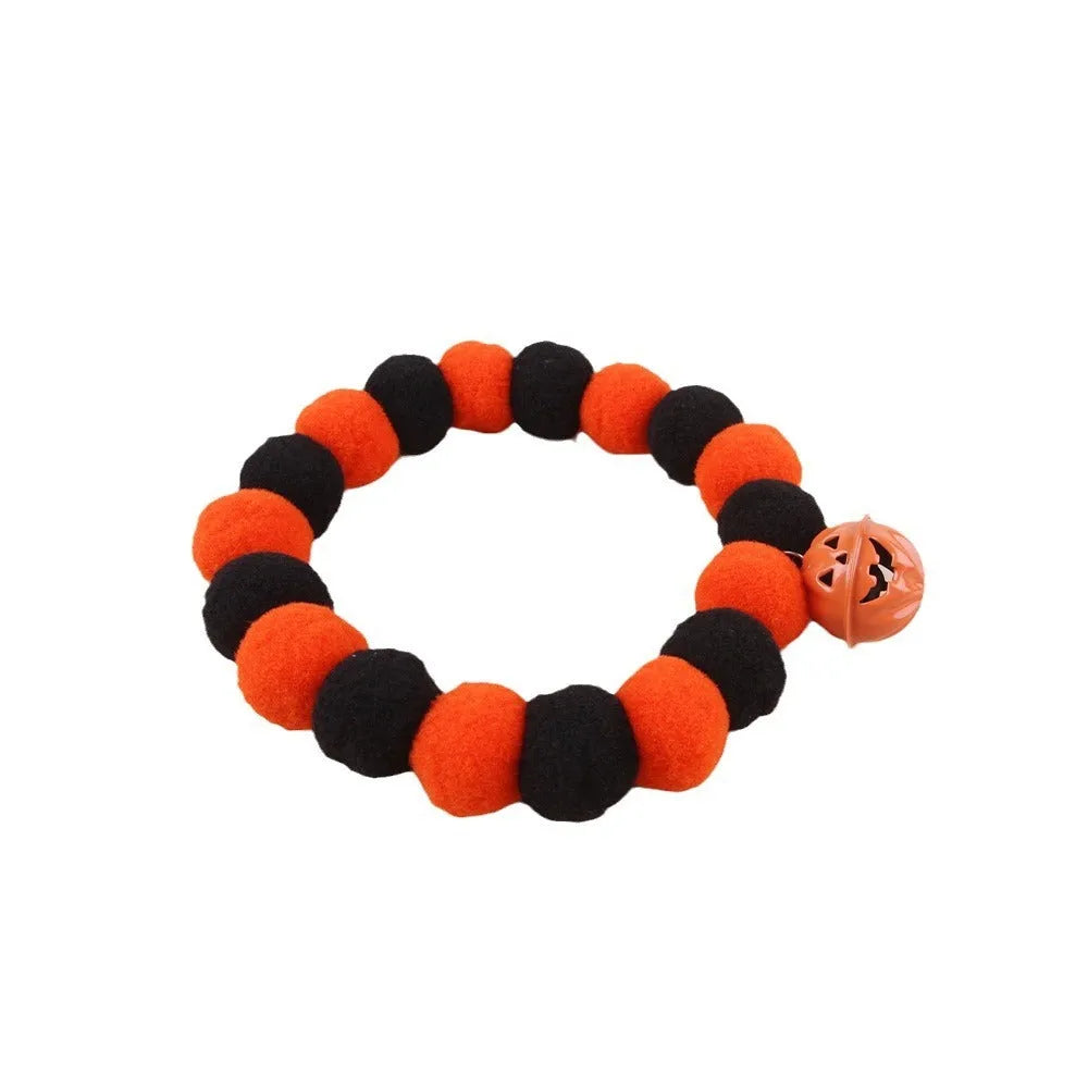 Orange Halloween cat collar with black jack-o'-lantern print and a small detachable fabric pumpkin basket.