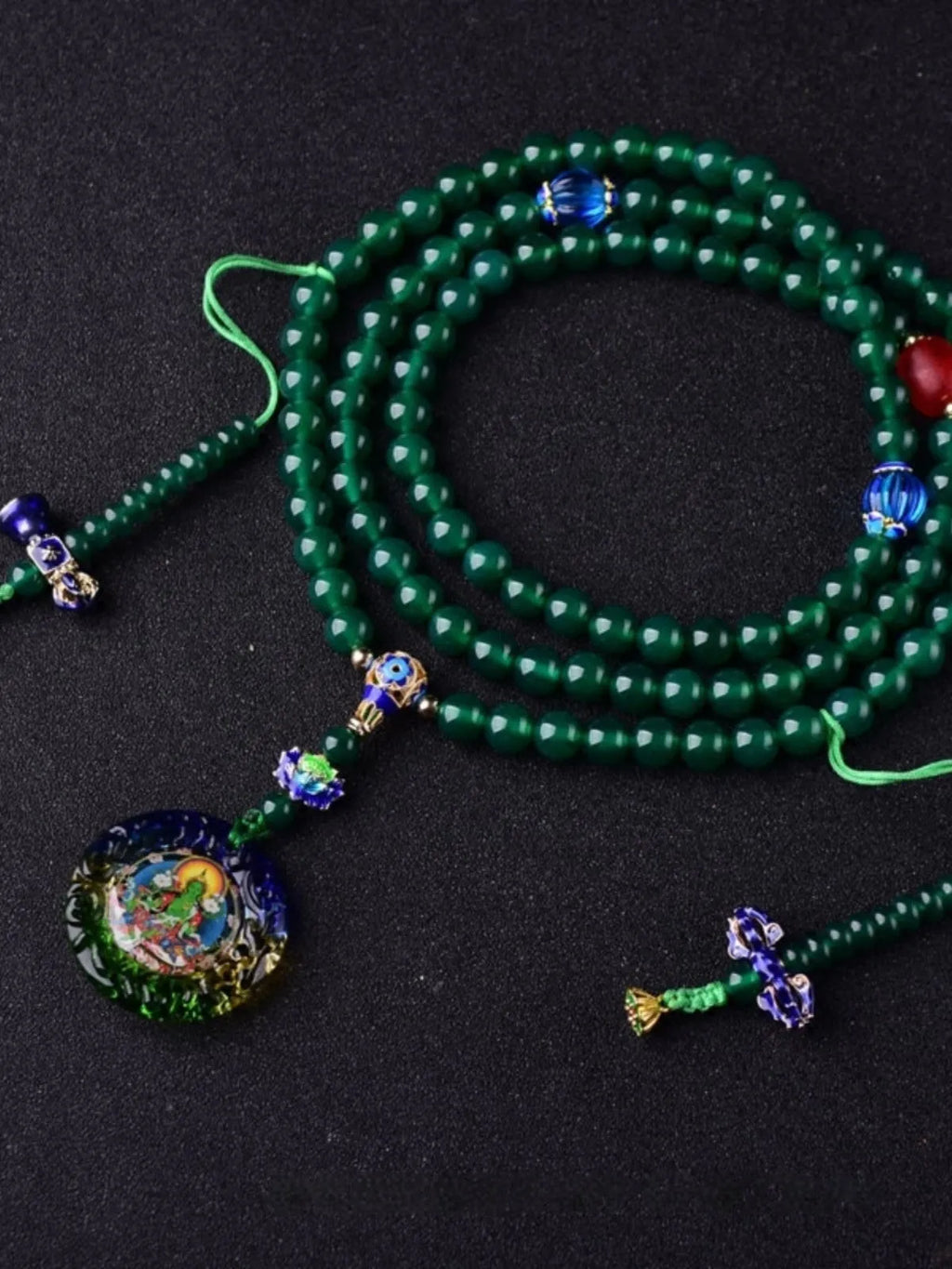 Natural green agate 108-bead bracelet with pendant in Thangka style on a wrist.