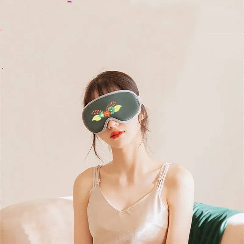 Pink and green portable eye SPA massage goggles with suede shell on a grey background.