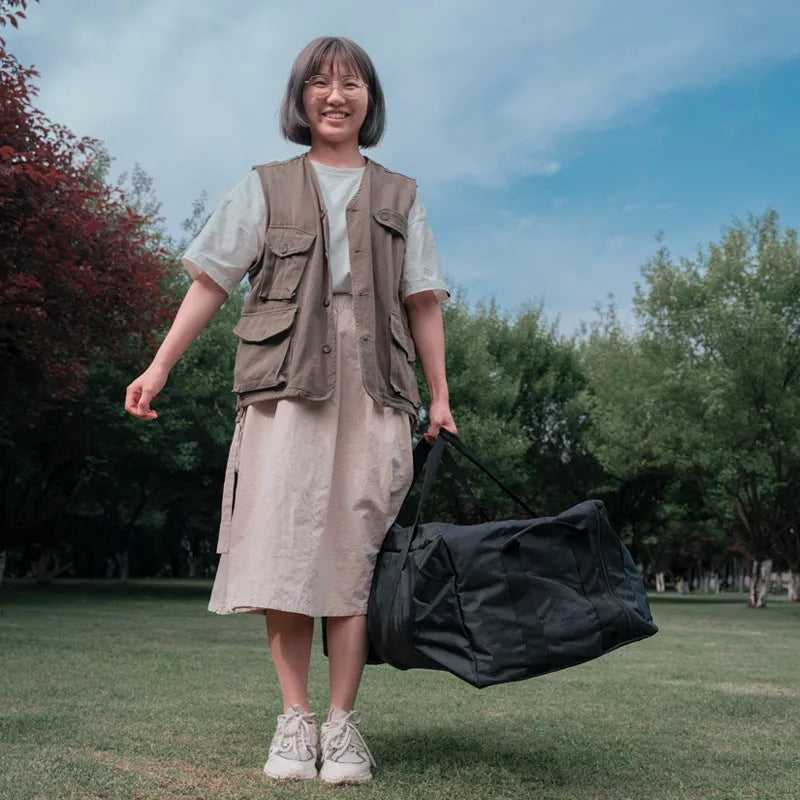 Green waterproof camping storage bag with carry handles, shown carrying a folding table and chairs.