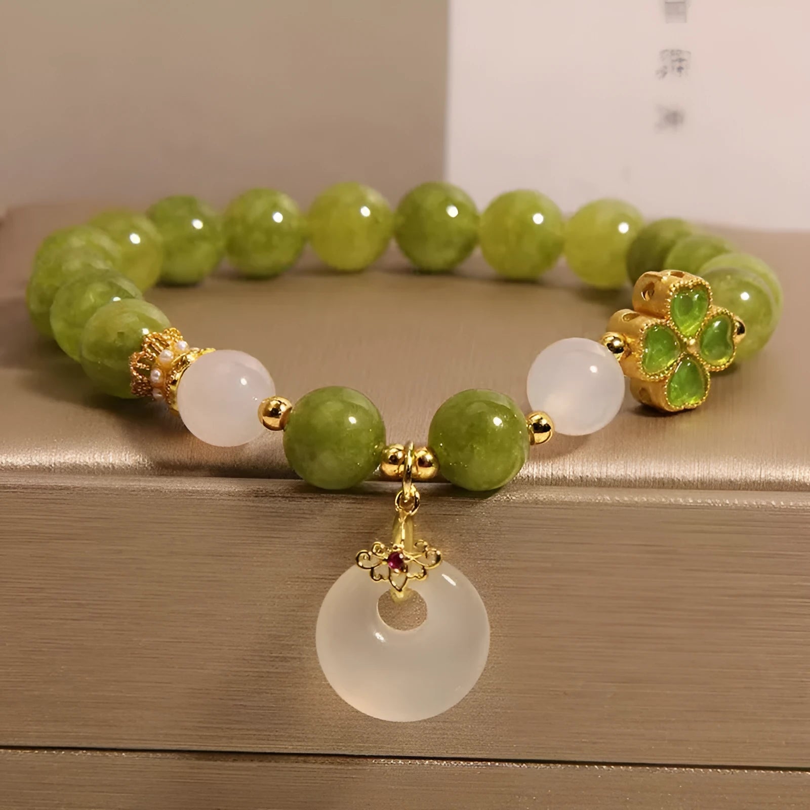 Green tourmaline four-leaf clover women's bracelet with safety buckle clasp on a white background.