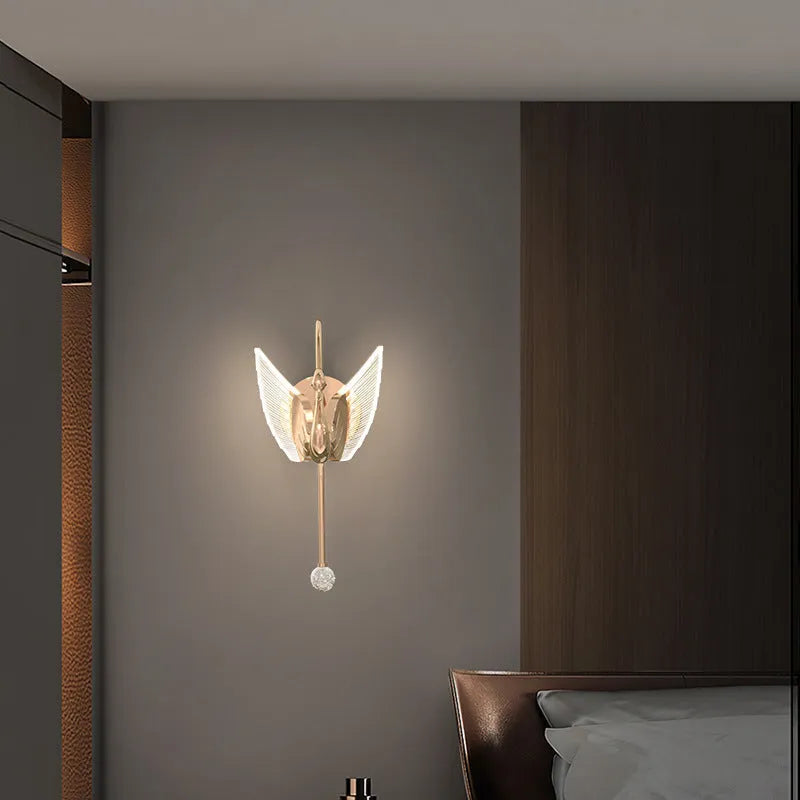 Gold minimalist swan wall lamp with acrylic shade mounted beside bed