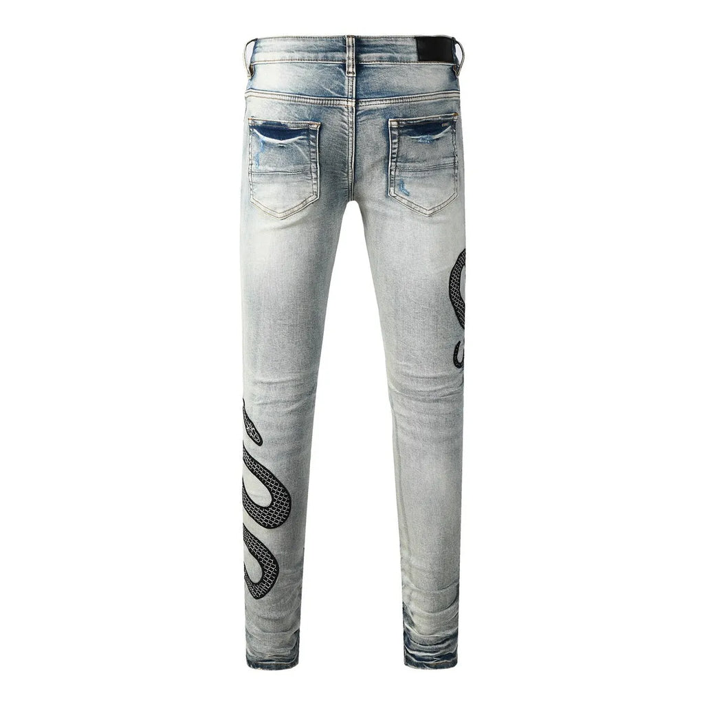 Man's blue distressed skinny jeans with a button fly and mid waist on a grey background.