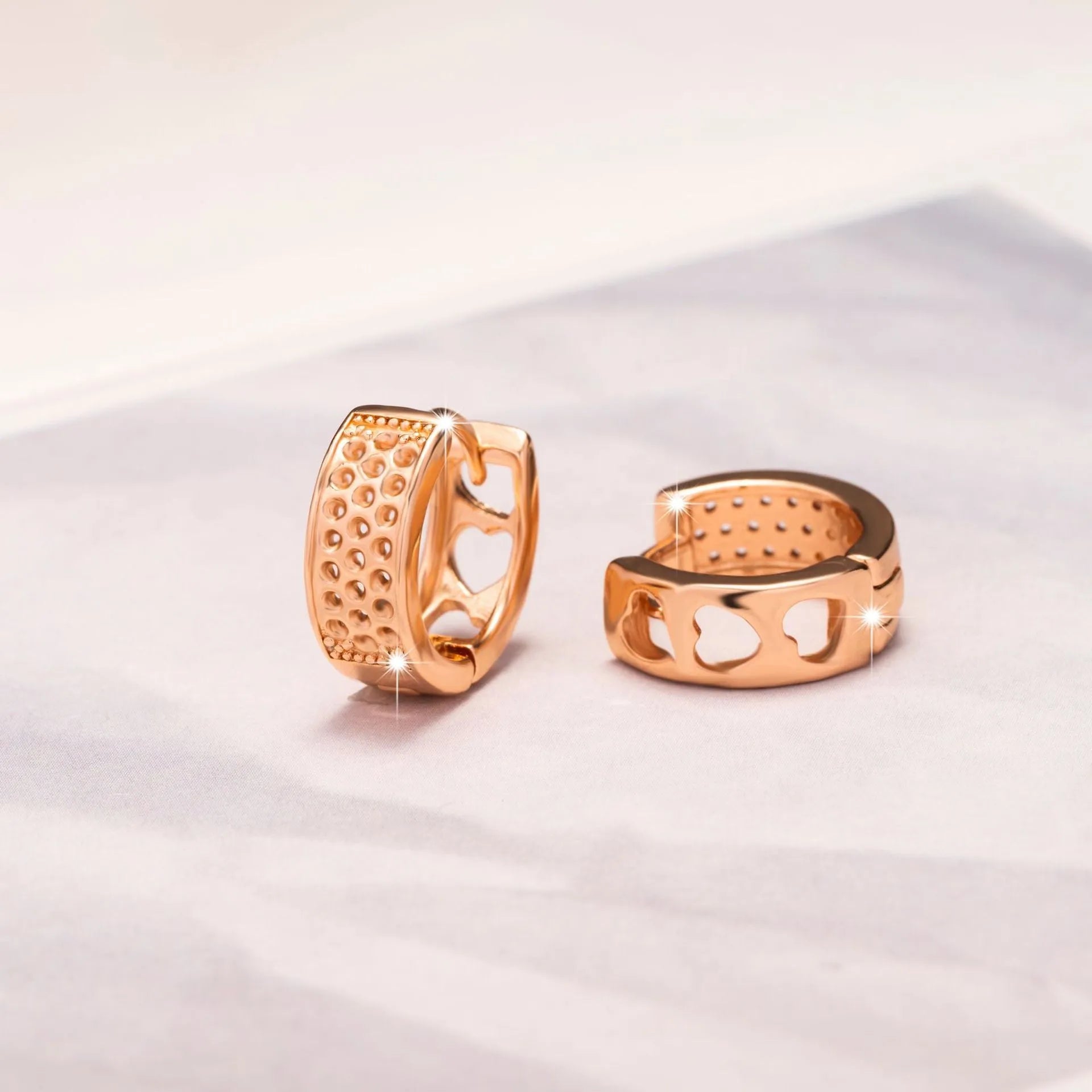 Rose gold electroplated earrings with three hollow heart shapes in circular arrangement
