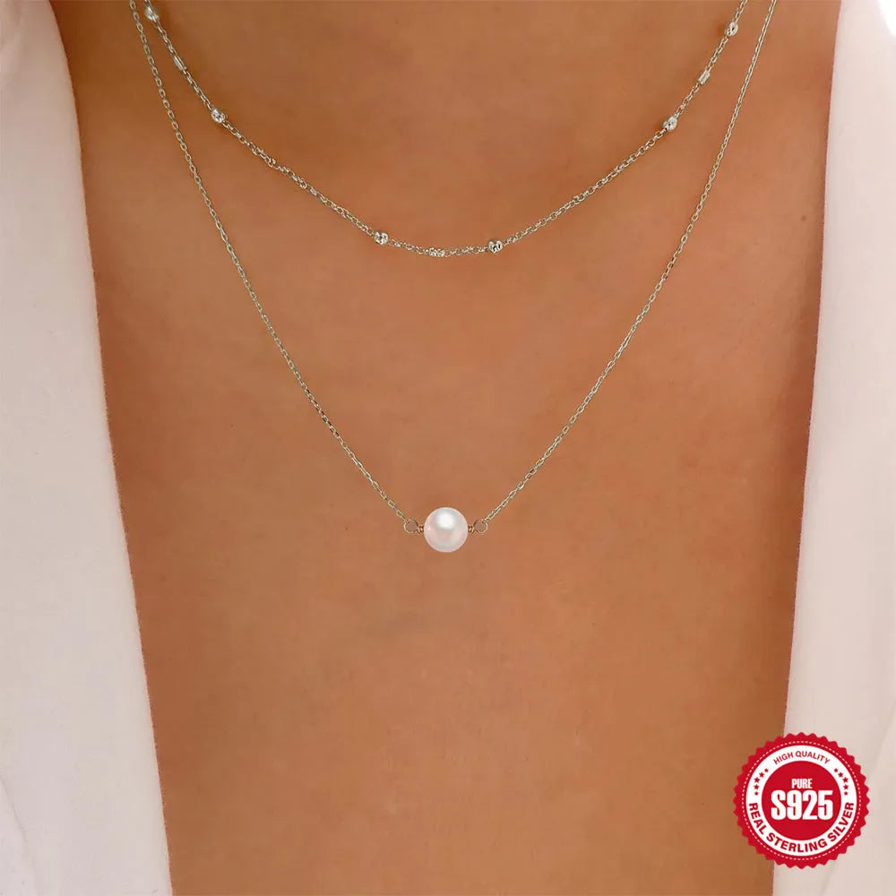 S925 sterling silver double layer necklace with twin pearls on a geometric pendant, shown in gold and white gold finishes.