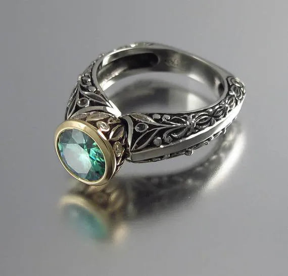 Gold-plated women's ring with flower design featuring green gemstone accents and colour separation details