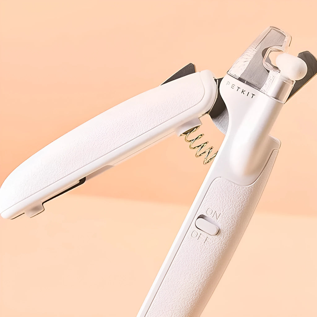 White pet nail clippers with LED light, anti-splash guard, and built-in file on a grey surface